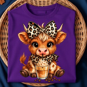 Puede incluir: Una sudadera morada con un dise&ntilde;o de vaca de dibujos animados. La vaca tiene un lazo y una bufanda con estampado de leopardo, y est&aacute; bebiendo caf&eacute;. El dise&ntilde;o incluye granos de caf&eacute;. La sudadera est&aacute; hecha de un material suave.