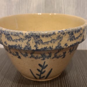 May include: A vintage blue and white ceramic mixing bowl with a floral design. The bowl is made of stoneware and has a rustic, farmhouse style.