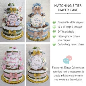May include: Three-tier diaper cake decorated with baby-themed decorations. The bottom tier is decorated with a green and gold ribbon, the middle tier is decorated with a blue and gold ribbon, and the top tier is decorated with a pink and gold ribbon. The cake is 15 inches by 12 inches and is available as a DIY kit.