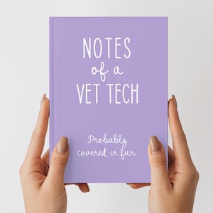 May include: A lavender notebook with the text "NOTES of a VET TECH" in white script. Below, the text reads "Probably covered in fur." The notebook is held by two hands against a white background.
