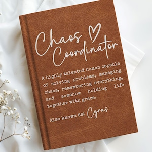 Op de afbeelding: Een bruin notitieboek met de woorden "Chaos Coordinator" in witte letters. De tekst eronder beschrijft een getalenteerd persoon die problemen oplost en chaos beheert. De naam "Cyrus" staat ook op het notitieboek.