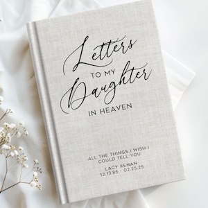May include: A beige linen-covered journal with the text "Letters to my Daughter in Heaven" and "All the things I wish I could tell you" in black script. The journal is personalized with the name "Lacy Kenan" and the dates "12.13.85 - 02.25.25".