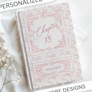May include: A personalized journal with a floral design in pink and white. The cover features the text "Chapter 18" and "Kayla Pate" in elegant script. The word "PERSONALIZED" is at the top, and "MORE DESIGNS" is at the bottom.