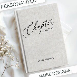 May include: A personalized journal with a light gray linen cover. The cover features the words "Chapter Sixty" in elegant script, with the name "Jean Jenkins" below. The word "Personalized" is at the top.