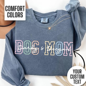 This personalized dog mom sweatshirt is so cute and comfortable. It says dog mom in a colorful text. You customize the overlay cursive font to say what you want. You can put your dog's names, dog breed, or nothing at all.