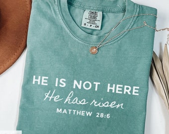 Puede incluir: Una camiseta verde claro con el texto "HE IS NOT HERE He has risen MATTHEW 28:6" impreso en blanco.