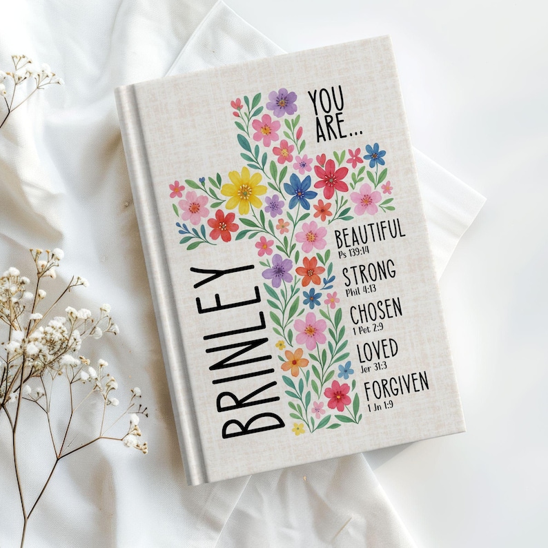 Personalized Christian journal for women and girls with a floral cross design on the cover. The front features “You Are” affirmations with Bible verses and a custom name option. Available in 8 colors, this faith-based notebook can be used for prayer journaling, Bible study notes, gratitude, reflections, and daily writing. Optional customization available for spine and back cover text. Feminine, inspirational gift idea for teens, women, church, or special occasions.
