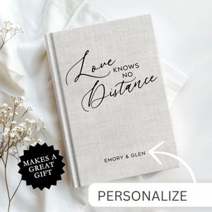 May include: A white linen journal with the text "Love Knows No Distance" in black script. The journal has a personalized inscription that reads "Emory & Glen".