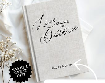 May include: A white linen journal with the text "Love Knows No Distance" in black script. The journal has a personalized inscription that reads "Emory & Glen".