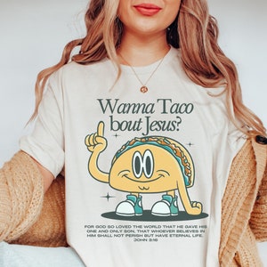 May include: A white t-shirt with a cartoon taco wearing sneakers and pointing upwards. The text "Wanna Taco bout Jesus?" is above the taco. The text "For God so loved the world that he gave his one and only Son, that whoever believes in him shall not perish but have eternal life. John 3:16" is below the taco.