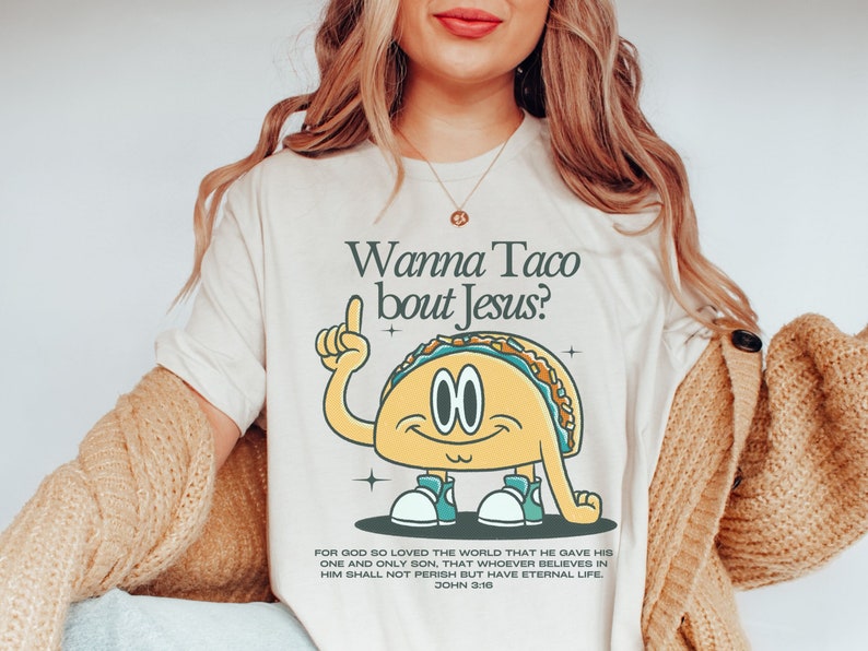May include: A white t-shirt with a cartoon taco wearing sneakers and pointing upwards. The text "Wanna Taco bout Jesus?" is above the taco. The text "For God so loved the world that he gave his one and only Son, that whoever believes in him shall not perish but have eternal life. John 3:16" is below the taco.