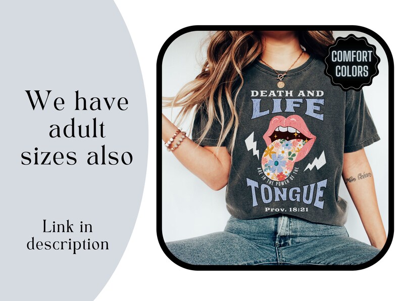 Pu&ograve; includere: T-shirt grigio scuro con le parole "DEATH AND LIFE" e "TONGUE" in stile vintage. La grafica della lingua presenta fiori e fulmini. Il testo "We have adult sizes also" &egrave; a sinistra.