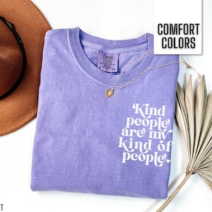 May include: Purple t-shirt with the text "Kind people are my kind of people." in white lettering. The shirt has a distressed look and is made of a soft, comfortable fabric.