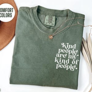 May include: A green t-shirt with the text "Kind people are my kind of people." printed in white on the front. The shirt is made of a soft, comfortable material and has a relaxed fit.