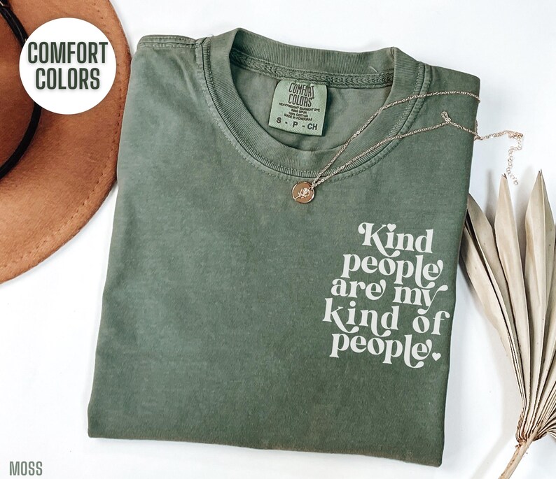 May include: A green t-shirt with the text "Kind people are my kind of people." printed in white on the front. The shirt is made of a soft, comfortable material and has a relaxed fit.