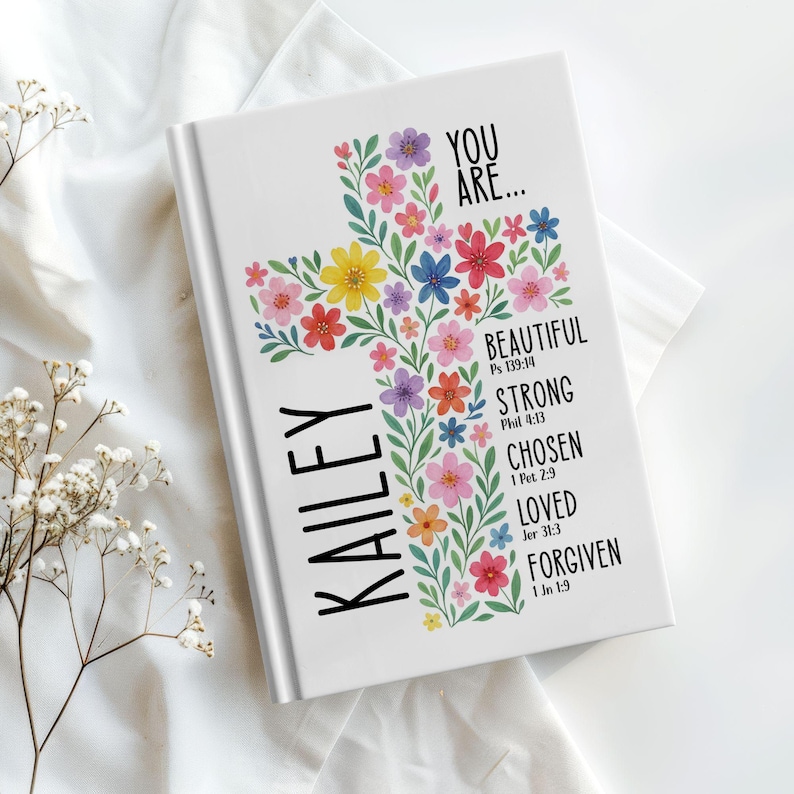 Personalized Christian journal for women and girls with a floral cross design on the cover. The front features “You Are” affirmations with Bible verses and a custom name option. Available in 8 colors, this faith-based notebook can be used for prayer journaling, Bible study notes, gratitude, reflections, and daily writing. Optional customization available for spine and back cover text. Feminine, inspirational gift idea for teens, women, church, or special occasions.