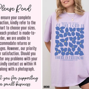 May include: A lavender t-shirt with a blue floral design and the text "Where the Spirit of the Lord is There is Freedom 2 Corinthians 5:17".