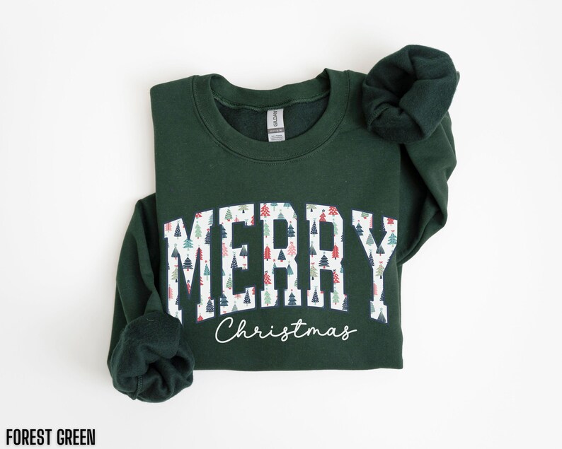 May include: Forest green sweatshirt with a white print that says "Merry Christmas" with a pattern of Christmas trees inside the letters.