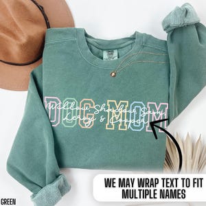 May include: Light green sweatshirt with the text "Dog Mom" in colorful letters. The text is surrounded by the names "Willow, Shadow, Sammy, Leroy & Cooper".