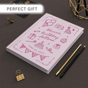 May include: A light pink journal with the text "Olivia's Birthday Letters" and decorative birthday-themed doodles. The date "June 25, 2025" is printed on the cover. Includes gold and black pencils.