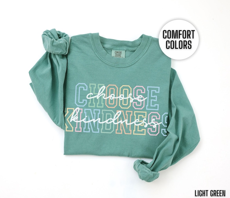 May include: Light green long-sleeve t-shirt with the text "Choose Kindness" in rainbow colors. The shirt is made of a soft, comfortable material.