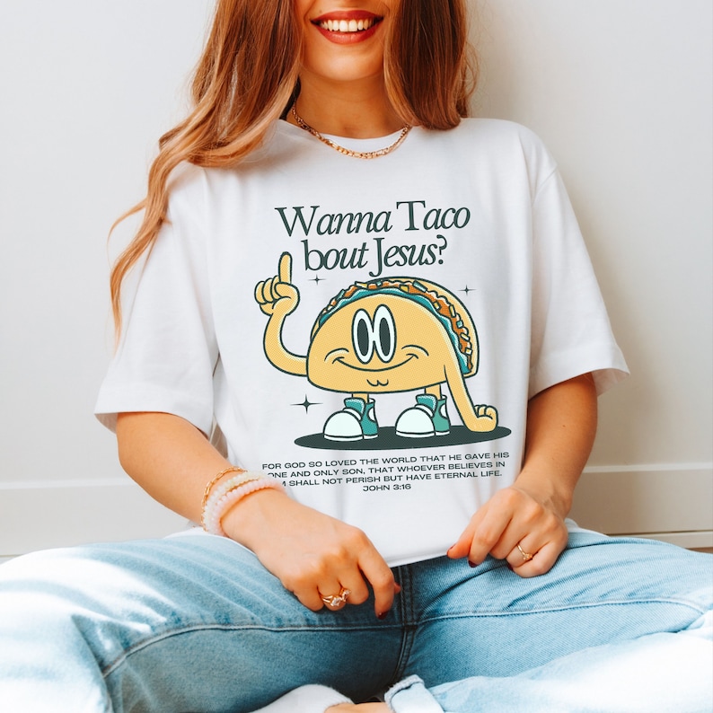 May include: White t-shirt with a cartoon taco wearing sneakers and a speech bubble that says "Wanna Taco bout Jesus?"  The text below the taco says "For God so loved the world that he gave his one and only Son, that whoever believes in him shall not perish but have eternal life. John 3:16"