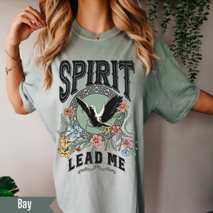 K&ouml;nnte beinhalten: Ein hellgr&uuml;nes T-Shirt mit einem Vintage-Grafikdesign mit einem Vogel mit Blumen und dem Text "SPIRIT LEAD ME".