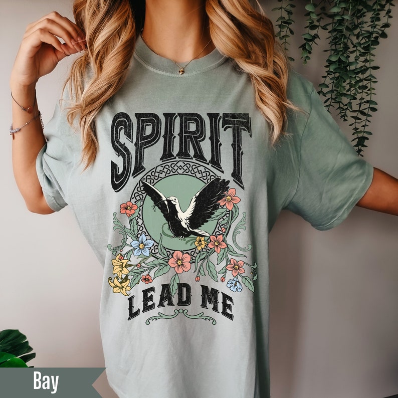 K&ouml;nnte beinhalten: Ein hellgr&uuml;nes T-Shirt mit einem Vintage-Grafikdesign mit einem Vogel mit Blumen und dem Text "SPIRIT LEAD ME".