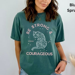 May include: A teal blue t-shirt with a white graphic of a tiger with the text "Be Strong & Courageous" and "Joshua 1:9".