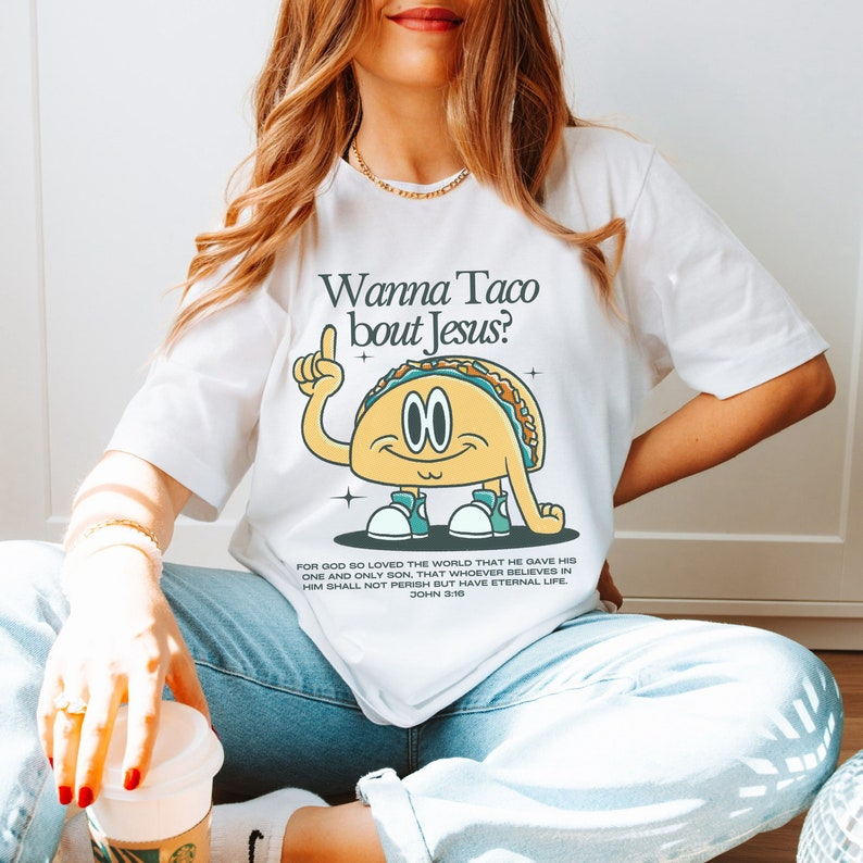 May include: White t-shirt with a cartoon taco graphic and the text "Wanna Taco bout Jesus?"  The taco is wearing sneakers and has a happy expression.  The text "FOR GOD SO LOVED THE WORLD THAT HE GAVE HIS ONE AND ONLY SON, THAT WHOEVER BELIEVES IN HIM SHALL NOT PERISH BUT HAVE ETERNAL LIFE. JOHN 3:16" is printed below the taco.