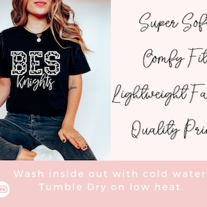 May include: Black t-shirt with the text "BES Knights" in a white, patterned font. The shirt also features the phrases "Super Soft", "Comfy Fit", "Lightweight Fabric", and "Quality Print". The care instructions are to wash inside out with cold water and tumble dry on low heat.