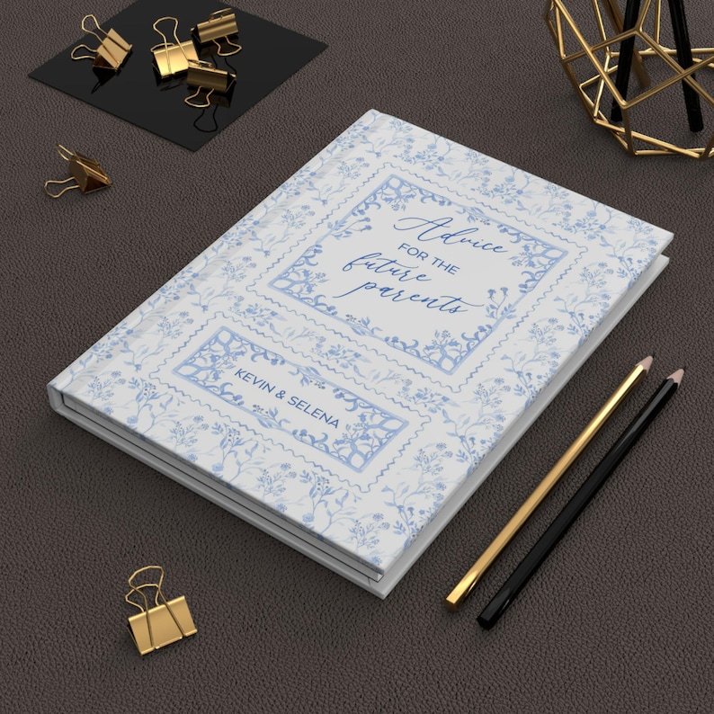 Op de afbeelding: Een wit dagboek met een blauw bloemenpatroon en de tekst "Advice for the future parents" in een decoratief kader. De namen "Kevin & Selena" staan in een kleiner kader onder de hoofdtekst.