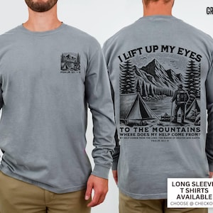 May include: Grey long-sleeve t-shirt with a mountain and camping graphic on the front and back. The back graphic includes the text "I lift up my eyes to the mountains" and "Where does my help come from?" Psalm 121:1-2.