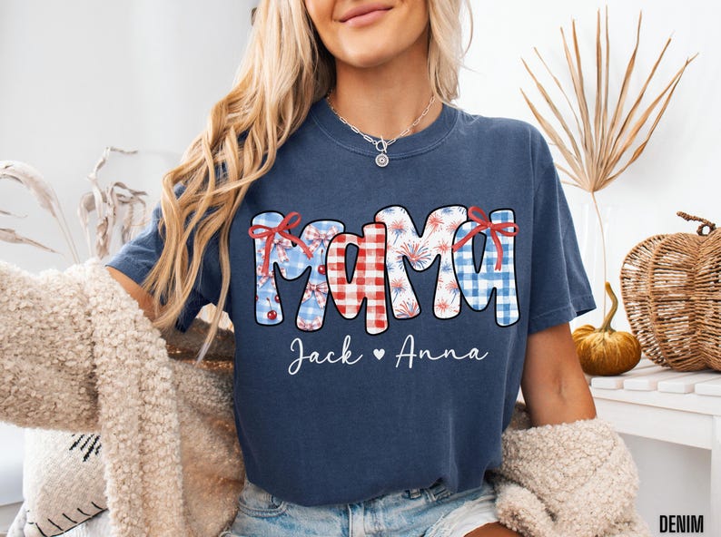 May include: Navy blue t-shirt with the word "MAMA" in a patriotic design, featuring red, white, and blue patterns and bows. The names "Jack" and "Anna" are written below the word "MAMA".
