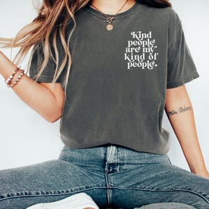 May include: A dark gray t-shirt with the text "Kind people are my kind of people." printed in white on the front.