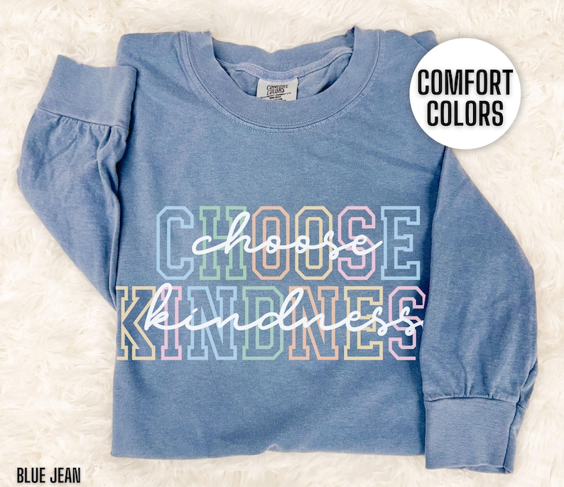 May include: A blue jean long-sleeve t-shirt with the text "Choose Kindness" in rainbow colors. The text is in a bold, blocky font.