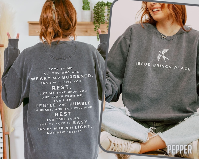 May include: A dark gray sweatshirt with a white graphic print that reads "Come to me. All you who are weary and burdened, and I will give you rest. Take my yoke upon you and learn from me. For I am gentle and humble in heart, and you will find rest for your souls. For my yoke is easy and my burden is light. Matthew 11:28-30". The sweatshirt also has a small white bird graphic on the right side with the text "Jesus brings peace".