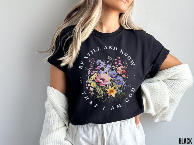 May include: Black cropped t-shirt with a floral design and the text "Be still and know that I am God" with the reference "Psalm 46:10".