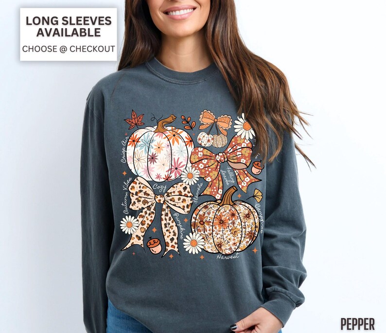 Puede incluir: Una camiseta de manga larga gris oscuro con un dise&ntilde;o de tem&aacute;tica oto&ntilde;al. El dise&ntilde;o incluye calabazas florales, lazos y las palabras "Autumn Vibes", "Cozy" y "Harvest". La camiseta tiene el texto "Long Sleeves Available Choose @ Checkout."