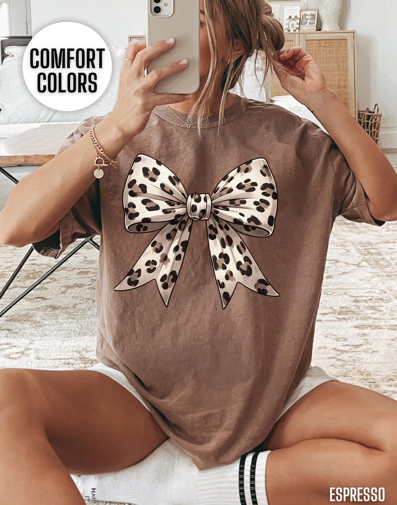 Puede incluir: Una camiseta marr&oacute;n con un gran lazo de estampado de leopardo en la parte delantera. La camiseta tiene un aspecto desgastado y est&aacute; hecha de una tela suave y c&oacute;moda.