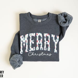 May include: Dark grey heather sweatshirt with a white graphic that says "Merry Christmas" with a pattern of colorful Christmas trees.