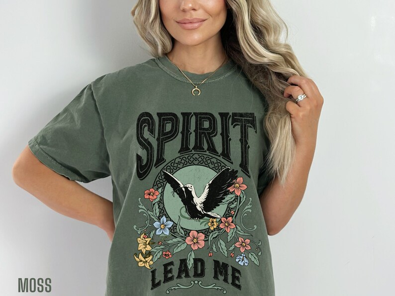 K&ouml;nnte beinhalten: Ein gr&uuml;nes T-Shirt mit einem Vintage-Motiv, das einen Vogel im Flug, Blumen und den Text "SPIRIT LEAD ME" zeigt.