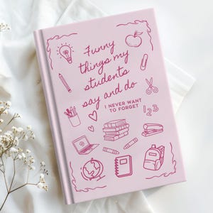 May include: Pink notebook with the title "Funny things my students say and do" and the text "I never want to forget". The notebook is decorated with various school-related drawings, including a lightbulb, an apple, a pencil, scissors, a stack of books, a laptop, a globe, a backpack, and a stapler.