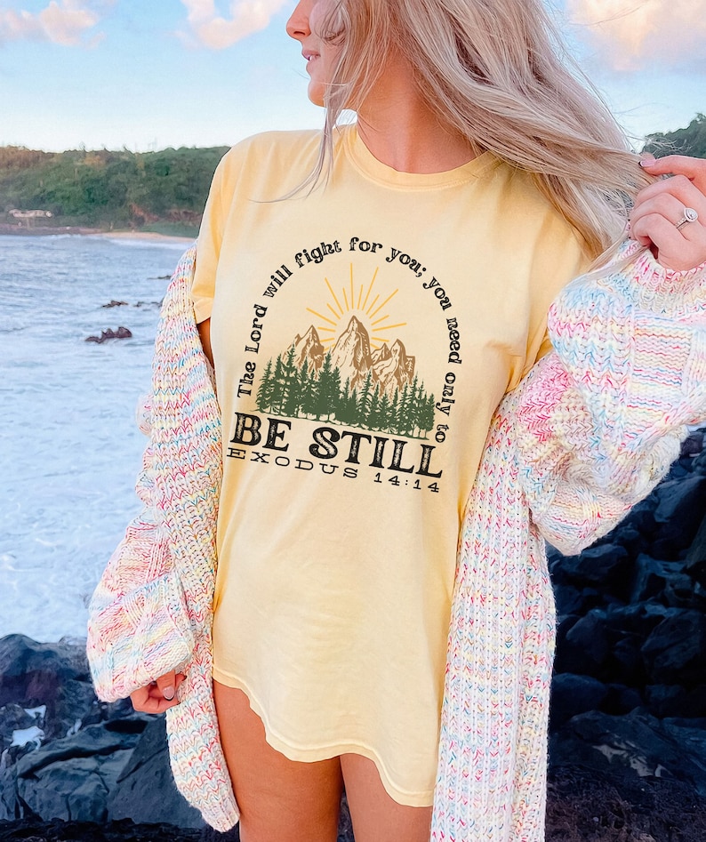 May include: A yellow t-shirt with a mountain scene and the text "The Lord will fight for you; you need only to be still. Exodus 14:14"