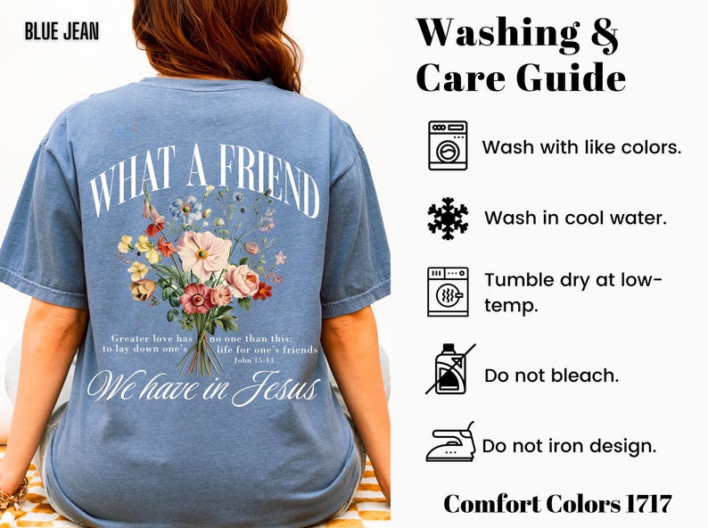 K&ouml;nnte beinhalten: Blaues Jeans-T-Shirt mit dem Text "WHAT A FRIEND" in einem Bogen. Darunter ein Blumenstrau&szlig;. Das Shirt enth&auml;lt auch den Text "We have in Jesus" und Waschanweisungen.