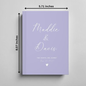 K&ouml;nnte beinhalten: Ein G&auml;stebuch in Lavendelfarbe mit den Namen "Maddie & Davis" in wei&szlig;er Kursivschrift. Der Text "Two Hearts, One Journey" und das Datum "June 30, 2023" sind ebenfalls in wei&szlig;er Kursivschrift. Das Buch misst 20,5 cm x 14,5 cm.