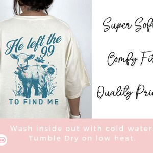 May include: A cream-coloured t-shirt featuring a teal graphic of a lamb and flowers, with the text "He left the 99 to find me." The shirt also has the words "Super Soft," "Comfy Fit," and "Quality Print."