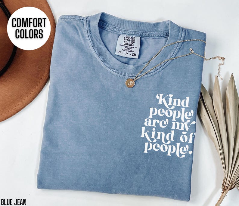 May include: A light blue t-shirt with the text "Kind people are my kind of people." printed in white. The shirt is made of a soft, comfortable material.