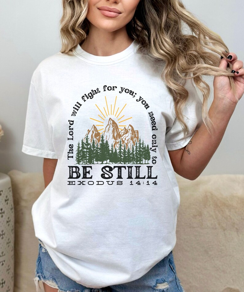 May include: White t-shirt with a mountain scene and the text "The Lord will fight for you; you need only to BE STILL EXODUS 14:14"