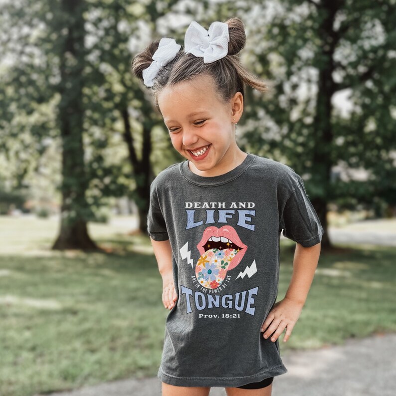 This Girls Christian Shirt is too cute.  Match with Mommy in this Bible verse T-shirt.  It says Death and life are in the power of the tounge. This is a trend Comfort Colors brand youth Christian graphic tee that comes in pepper, black, white.